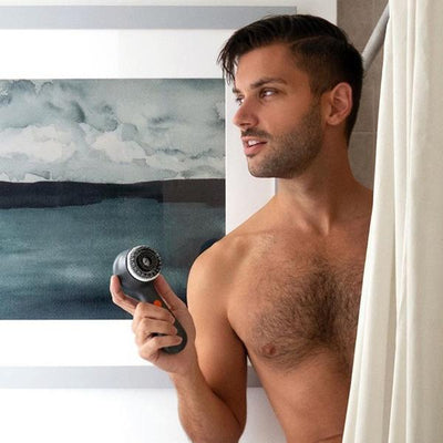Mandlig model, der træder ud af bruseren med Clarisonic Mia Men Sonic Facial Cleansing Device med børstehoved af trækul i hånden